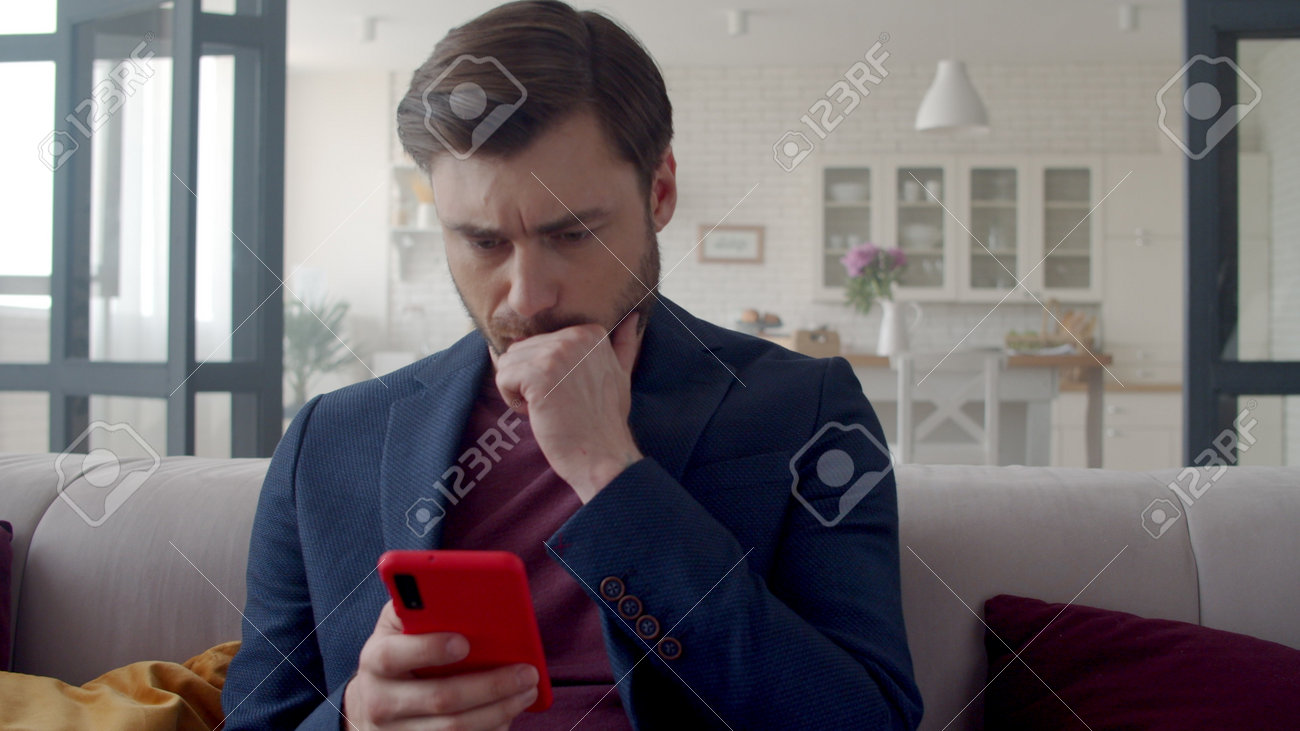 Closeup upset business man reading bad news on mobile phone at home office. Worried guy looking on phone in slow motion. Portrait of disappointed man feeling sad from negative news on couch. - 162271313 Closeup upset business man reading bad news on mobile phone at home office. Worried guy looking on phone in slow motion. Portrait of disappointed man feeling sad from negative news on couch. - 162271313
