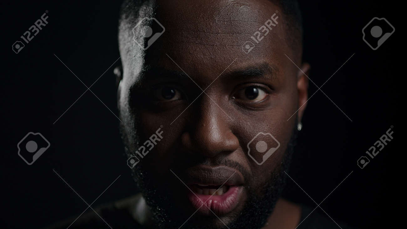 Closeup african american man crying on black background. Portrait of frustrated male person looking at camera in studio. Shocked afro guy yelling indoors. - 158355132 Closeup african american man crying on black background. Portrait of frustrated male person looking at camera in studio. Shocked afro guy yelling indoors. - 158355132