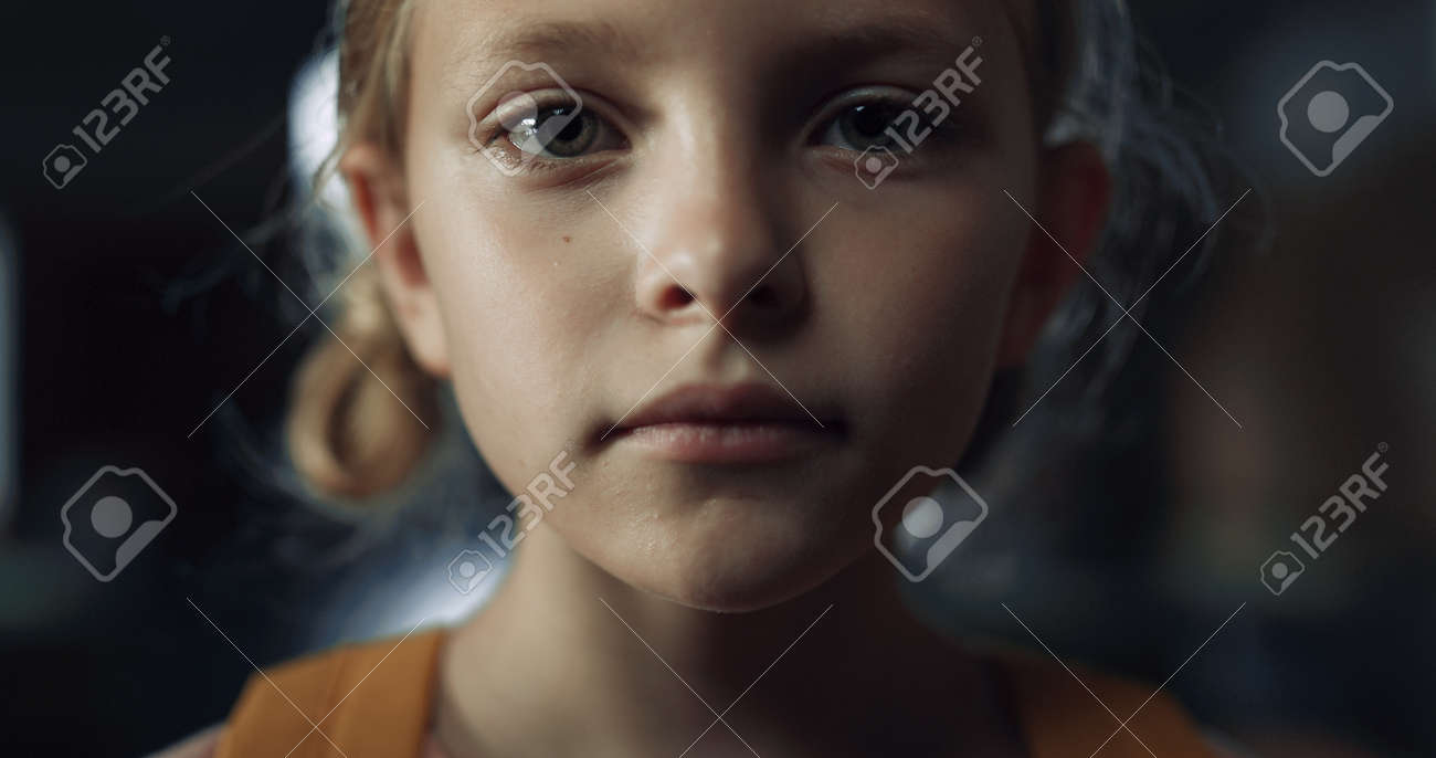 女子小学生　接写 暗いホールで小さな怖い女の子の接写。空の学校の廊下に一人で立っているおびえたプレティーンの女子高生。不幸な小学生の子どもがカメラを見て落ち込んでいる。孤独のコンセプト。の写真素材・画像素材  Image 189901183