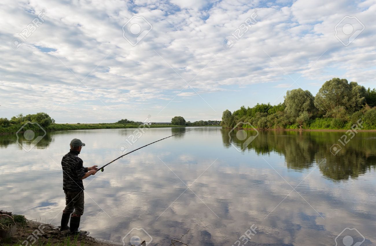 fishing in river a fisherman with a fishing rod on the river stock