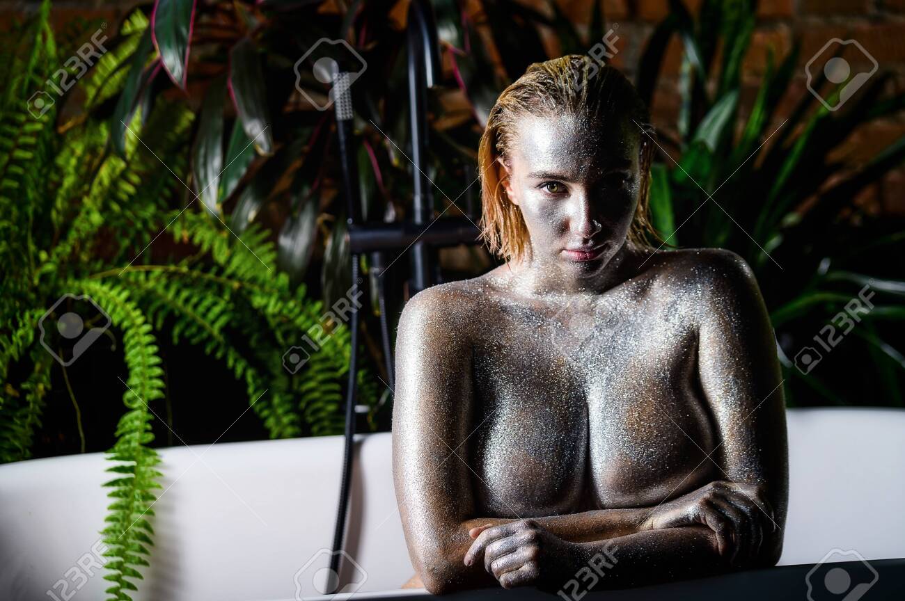 Nude Woman With Very Large Breasts With Silver Bodyart In The Bathroom. A  Girl With An Extra Large Bust With Sparkles On Her Skin Takes A Shower.  Stock Photo, Picture and Royalty