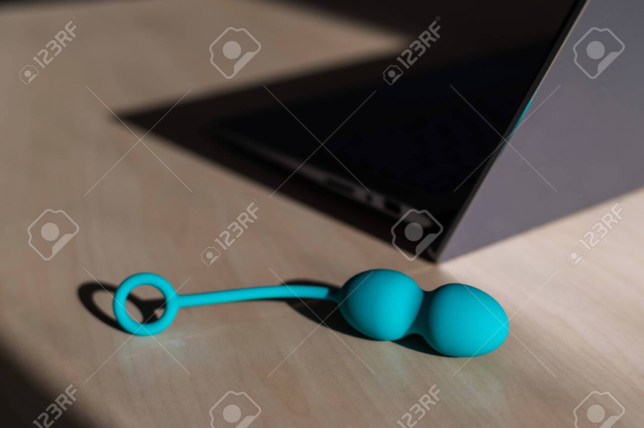 Blue silicone vaginal kegel balls on a table next to a laptop. Sex toy for building is synchronized with a computer. Intimate muscle trainer for women health. - 146952953 Blue silicone vaginal kegel balls on a table next to a laptop. Sex toy for building is synchronized with a computer. Intimate muscle trainer for women health. - 146952953