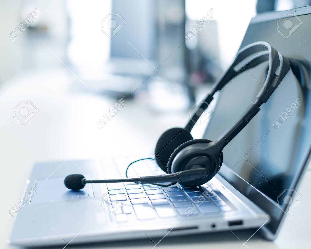 Call center operator desktop. Close-up of a headset on a laptop. Help desk. Workplace of a support service employee. Headphones with a microphone for voip on a computer keyboard - 150201756 Call center operator desktop. Close-up of a headset on a laptop. Help desk. Workplace of a support service employee. Headphones with a microphone for voip on a computer keyboard - 150201756