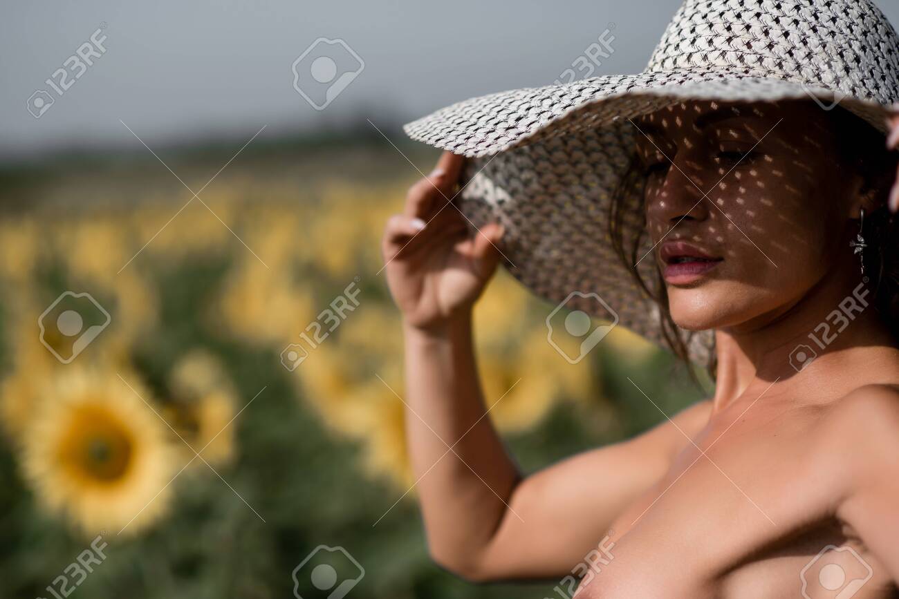 Mujer Desnuda En Un Campo De Girasoles. Una Hermosa Sombra Cae Sobre La  Cara Del Sombrero. El Sol Se Rompe A Través De Los Agujeros. Labios  Sensuales. Lujosa Figura Atlética Con Grandes