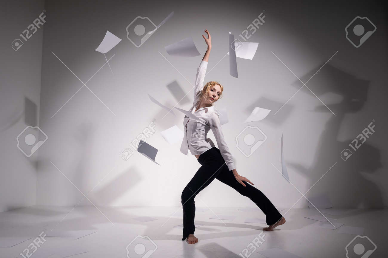A graceful ballerina in a business suit throws documents in the studio. Business woman dance barefoot on a white background - 170510359 A graceful ballerina in a business suit throws documents in the studio. Business woman dance barefoot on a white background - 170510359