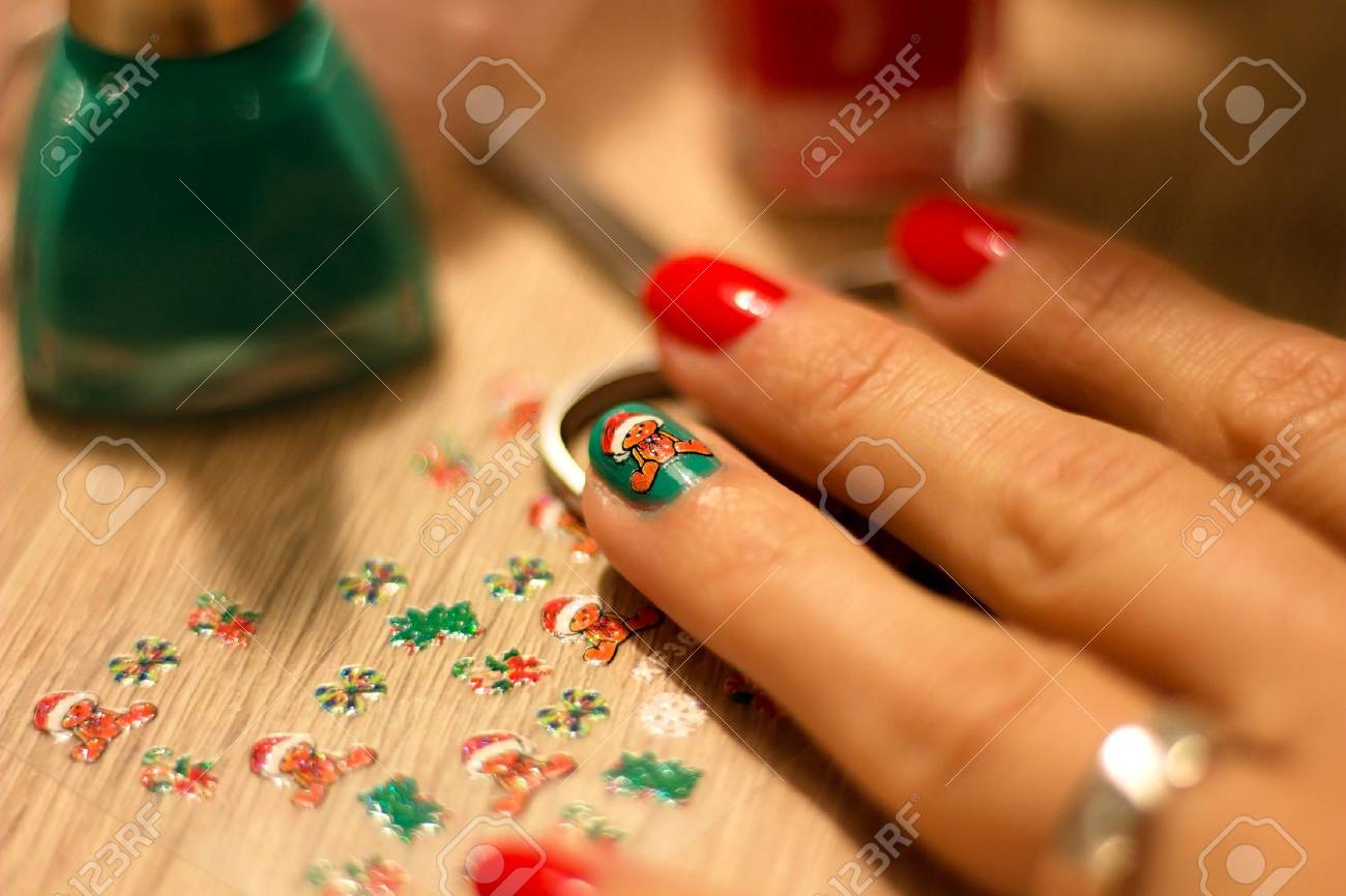hands of a young woman who paints her nails red and green nail..