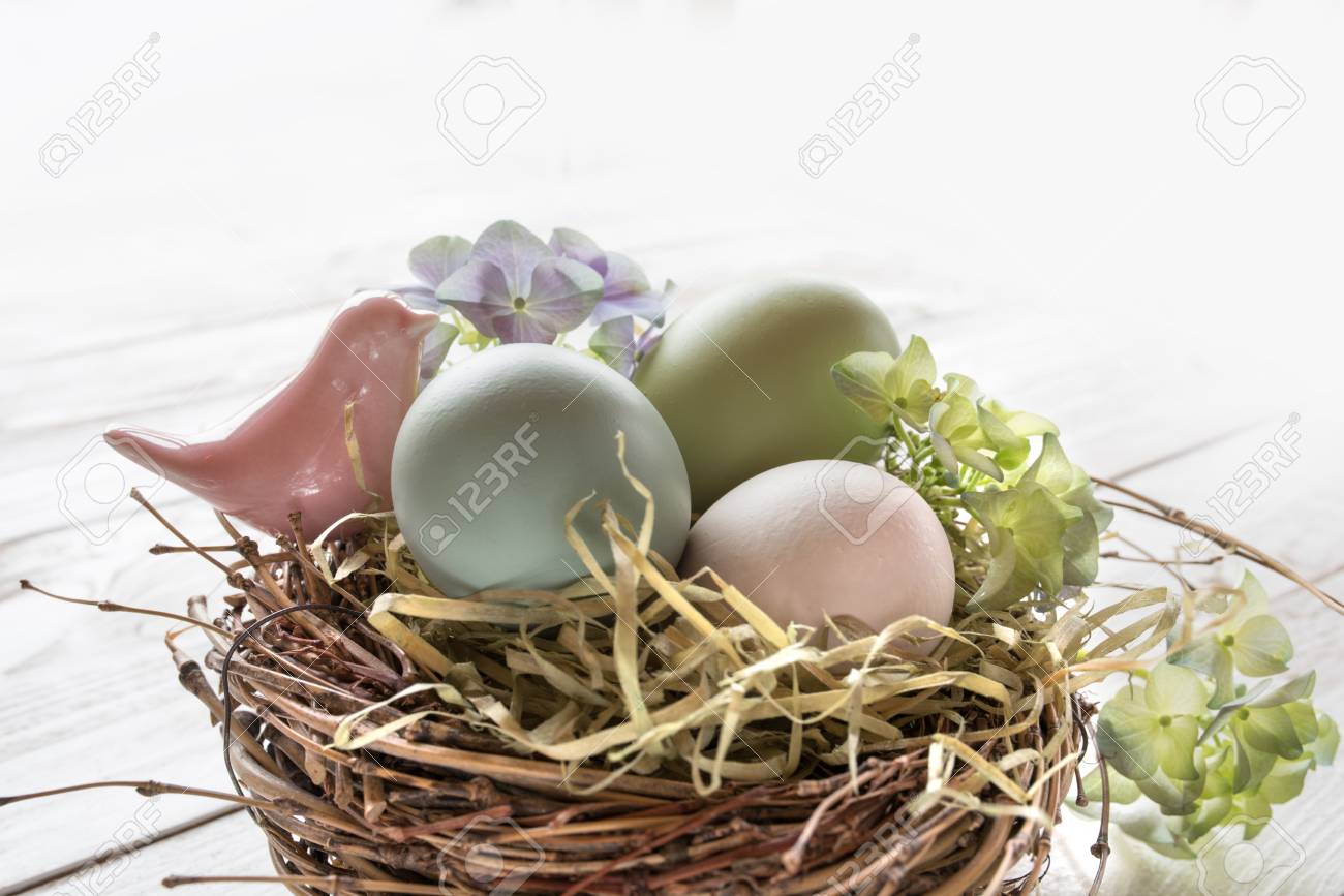 Oeufs De Pâques Aux Couleurs Pastel Avec Un Petit Oiseau Rose Dans Un Nid De Paille