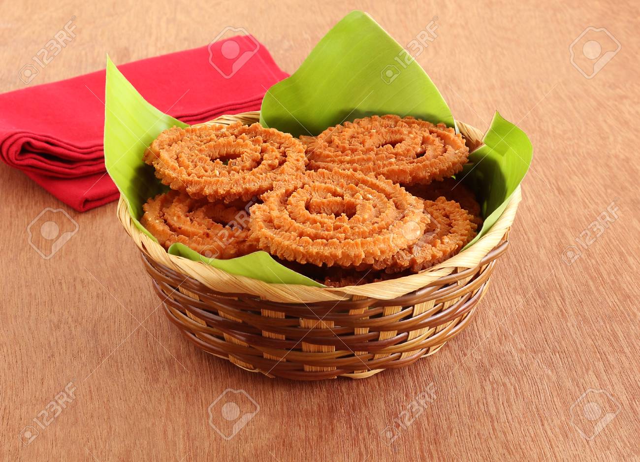 Chakli or chakkuli is a traditional, popular, vegetarian and delicious Indian savory snack, typically, made during some festivals, on a banana leaf in a basket on a wooden background. - 113296716 Chakli or chakkuli is a traditional, popular, vegetarian and delicious Indian savory snack, typically, made during some festivals, on a banana leaf in a basket on a wooden background. - 113296716