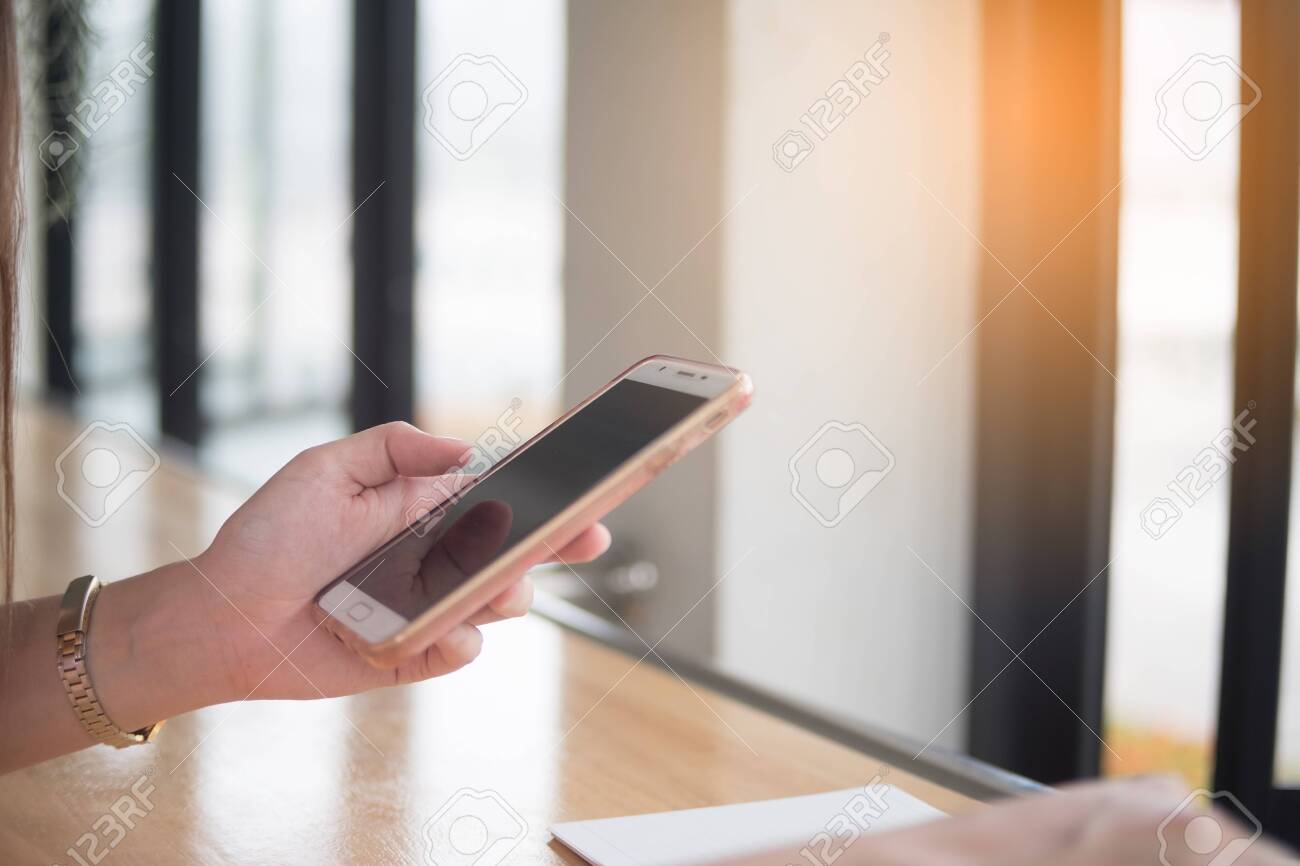 Woman use mobile phone at sitting on the desk, business technology concept, close up - 122663449 Woman use mobile phone at sitting on the desk, business technology concept, close up - 122663449