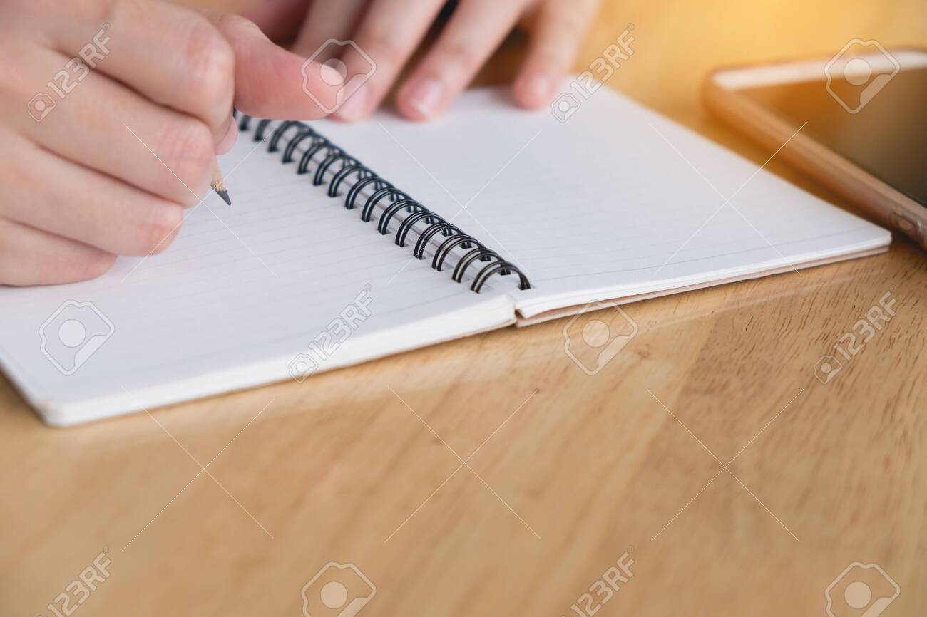 Close up. Woman hand is writting on notepad with pencil. Working business concept - 122663464 Close up. Woman hand is writting on notepad with pencil. Working business concept - 122663464