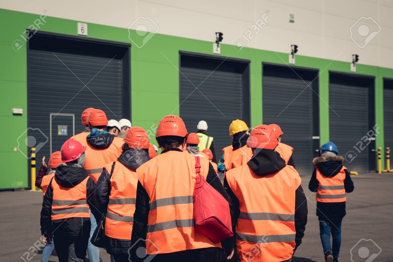 Un Grupo De Personas Con Cascos Naranjas Y Chalecos Reflectantes Visitando Una Fábrica O Almacén Desde Detrás De Vista. Fotos, Retratos, Imágenes Y Fotografía De Archivo Libres De Derecho. Image 78474259.
