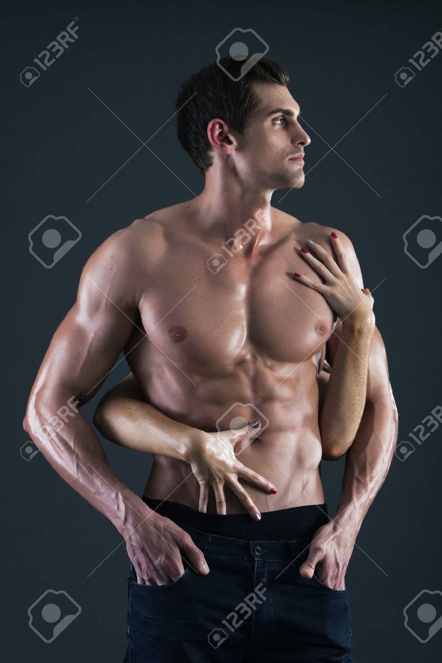 セクシーな筋肉質の上半身裸の男と彼の胸の女性両手 の写真素材 画像素材 Image
