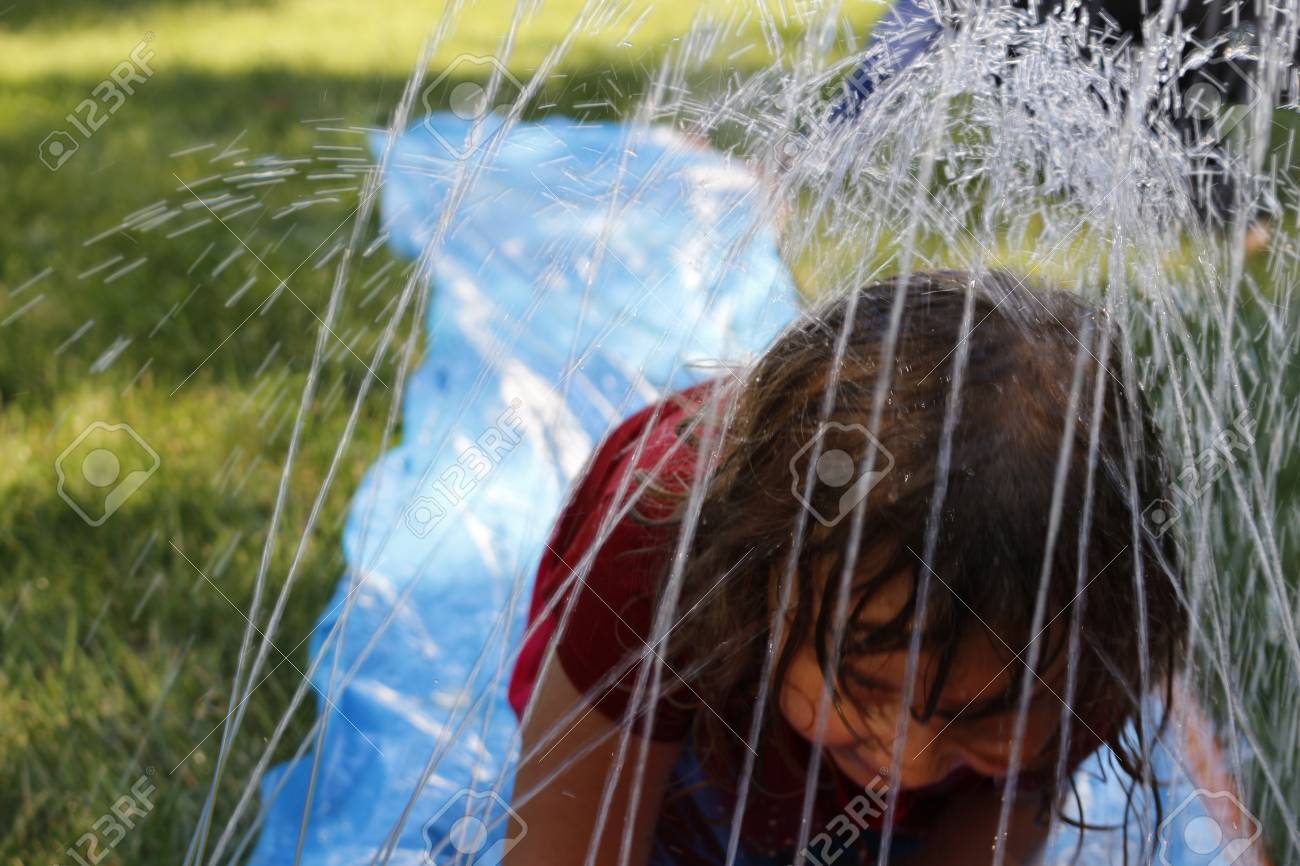 Little Preschool Girl Runs Through A Backyard Slip And Slide