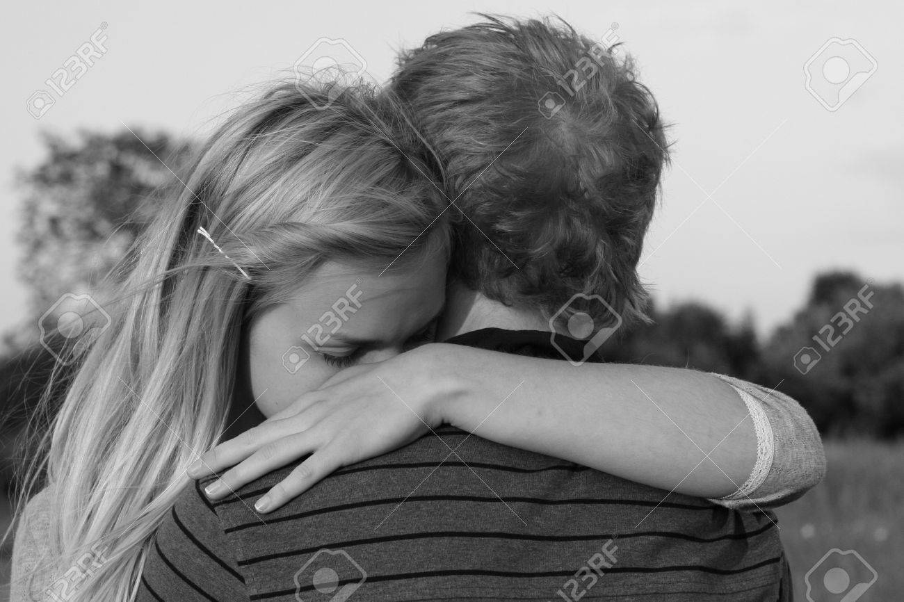 young teenage couple hugging girls face visible over boys shoulder
