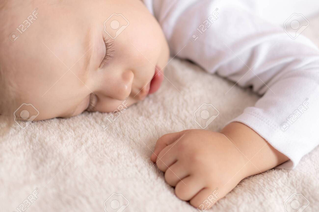 Childhood, sleep, rest, family, lifestyle concept - close-up portrait of a cute little boy of 2 years old in a white body sleeping on a beige bed at noon with mouth open top and side view. - 145842370 Childhood, sleep, rest, family, lifestyle concept - close-up portrait of a cute little boy of 2 years old in a white body sleeping on a beige bed at noon with mouth open top and side view. - 145842370