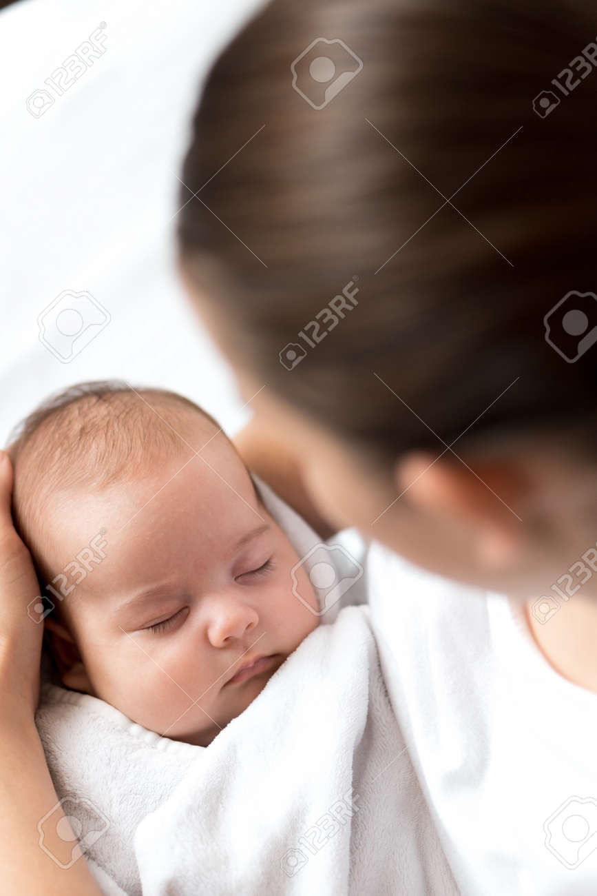 close-up portrait of mom with newborn baby on white background copy space. Young cute caucasian woman black haired holding child in arms motherhood, infancy, childhood, family, Mothers day concept - 164685955 close-up portrait of mom with newborn baby on white background copy space. Young cute caucasian woman black haired holding child in arms motherhood, infancy, childhood, family, Mothers day concept - 164685955