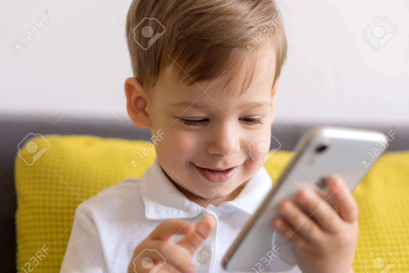 close-up happy little cute preschool baby boy talking video conference by smartphone in living room at home on yellow gray sofa with happiness smile. Childhood, online communication, tehnology concept - 166788937 close-up happy little cute preschool baby boy talking video conference by smartphone in living room at home on yellow gray sofa with happiness smile. Childhood, online communication, tehnology concept - 166788937