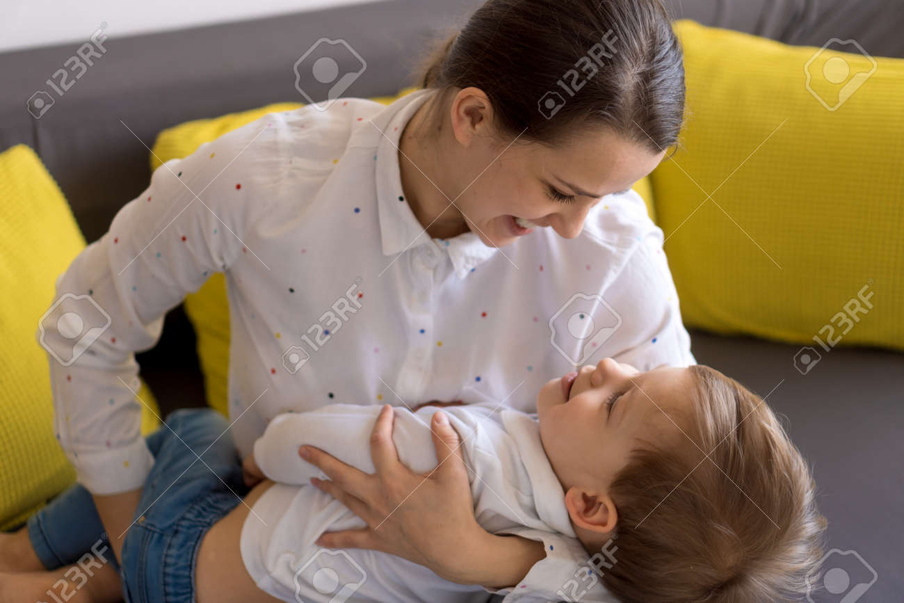 caucasian family little preschool baby boy and mom young woman hug joyfully together in living room at home with happiness smile. Child son congratulates on Mothers Day. Motherhood, childhood concept - 166788939 caucasian family little preschool baby boy and mom young woman hug joyfully together in living room at home with happiness smile. Child son congratulates on Mothers Day. Motherhood, childhood concept - 166788939