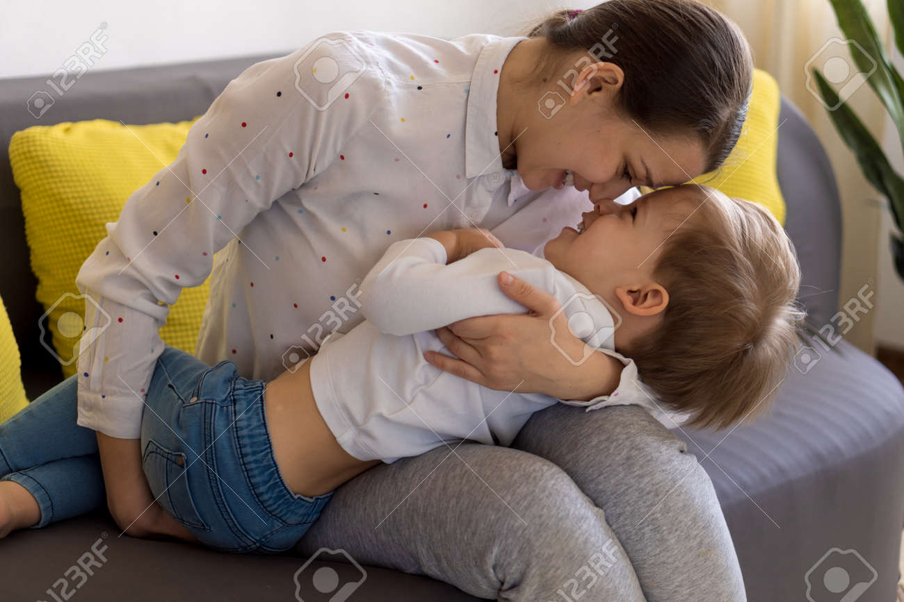 caucasian family little preschool baby boy and mom young woman hug joyfully together in living room at home with happiness smile. Child son congratulates on Mothers Day. Motherhood, childhood concept - 166761548 caucasian family little preschool baby boy and mom young woman hug joyfully together in living room at home with happiness smile. Child son congratulates on Mothers Day. Motherhood, childhood concept - 166761548
