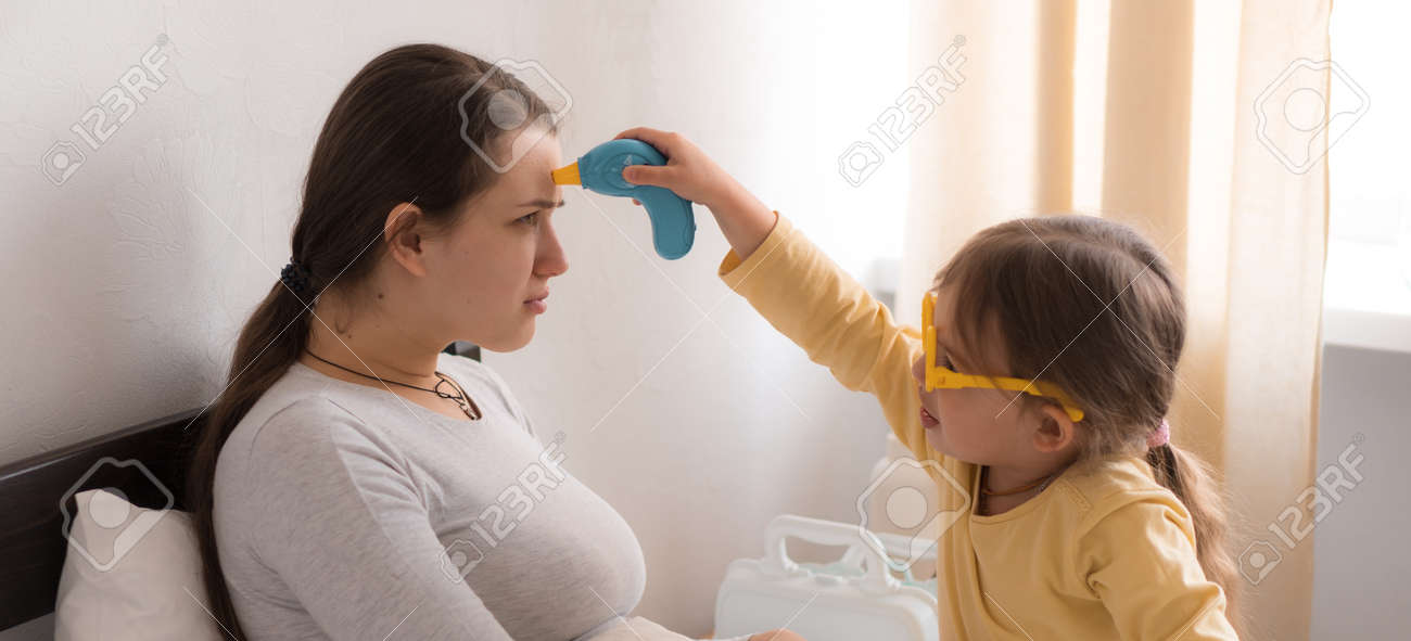 little girl wearing uniform playing doctor, nurse with young mum, nanny in bedroom, checking mother throat, measures temperature, take care, family spend leisure time at home together role play game - 167137502 little girl wearing uniform playing doctor, nurse with young mum, nanny in bedroom, checking mother throat, measures temperature, take care, family spend leisure time at home together role play game - 167137502