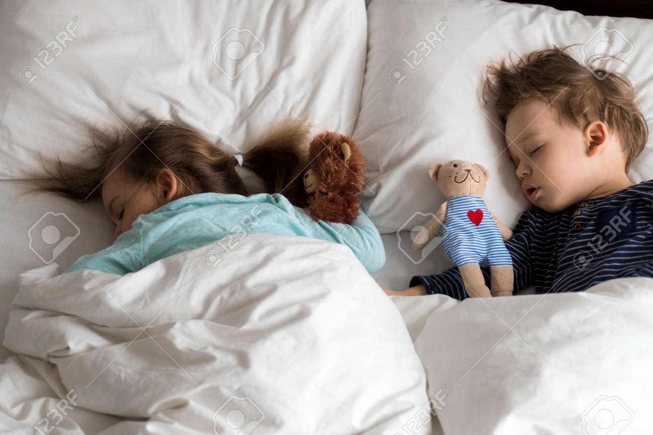 Authentic portrait cute caucasian little preschool siblings baby boy and girl in blue sleep with teddy bear on white bed. child resting at lunchtime. care, medicine and health, Childhood, life concept - 167094233 Authentic portrait cute caucasian little preschool siblings baby boy and girl in blue sleep with teddy bear on white bed. child resting at lunchtime. care, medicine and health, Childhood, life concept - 167094233