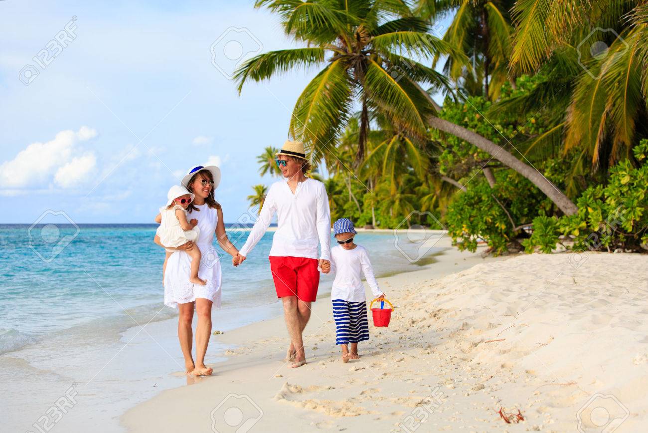 familia joven con dos niños caminando en la playa tropical
