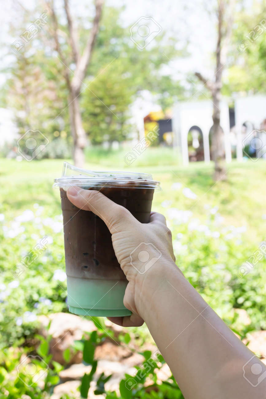 Female hand holding iced coffee drink in disposable take away cup, stock photo - 168400232 Female hand holding iced coffee drink in disposable take away cup, stock photo - 168400232