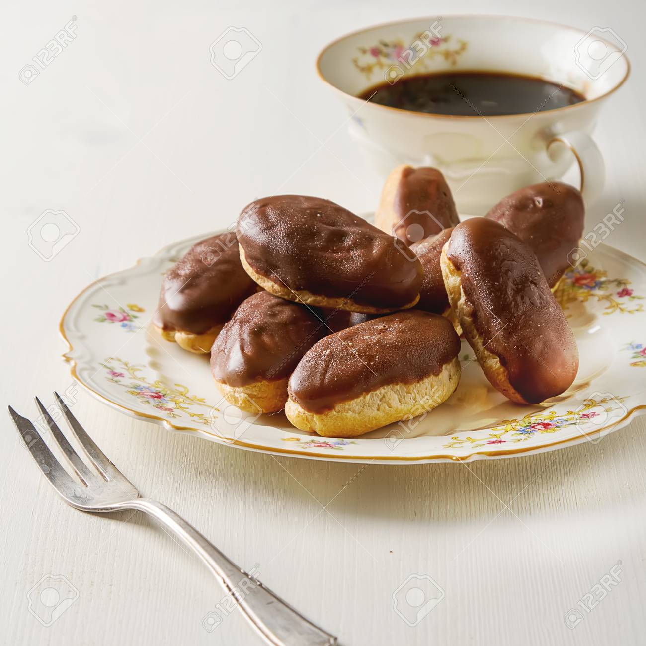 Gateau Au Chocolat Francais Eclairs Avec Une Tasse De Cafe Noir Chaud Dans Une Vaisselle Vintage Fourchette A Dessert Fond En Bois Blanc Banque D Images Et Photos Libres De Droits Image