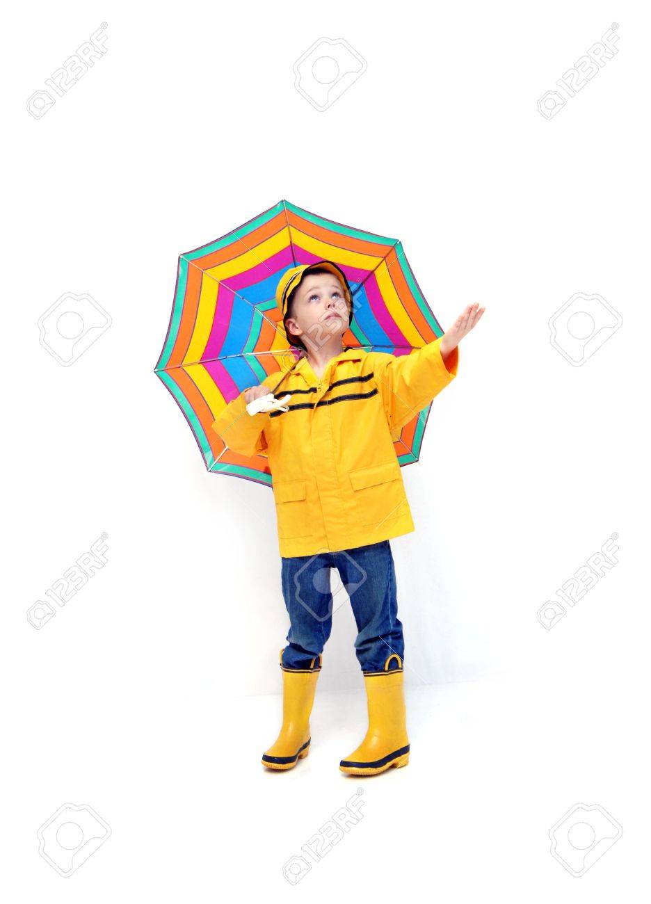 Chico joven en impermeable amarillo y botas de goma extiende la mano para comprobar si hay