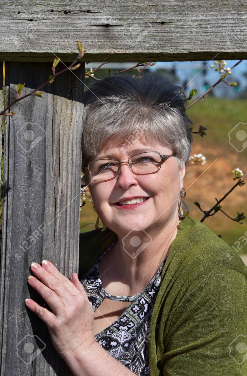 Next Door Neighbor Peeks Through The Hole In The Fence. She Is Wearing  Glasses And Is An Older Mature Woman. Stock Photo, Picture And Royalty Free  Image. Image 147143067.