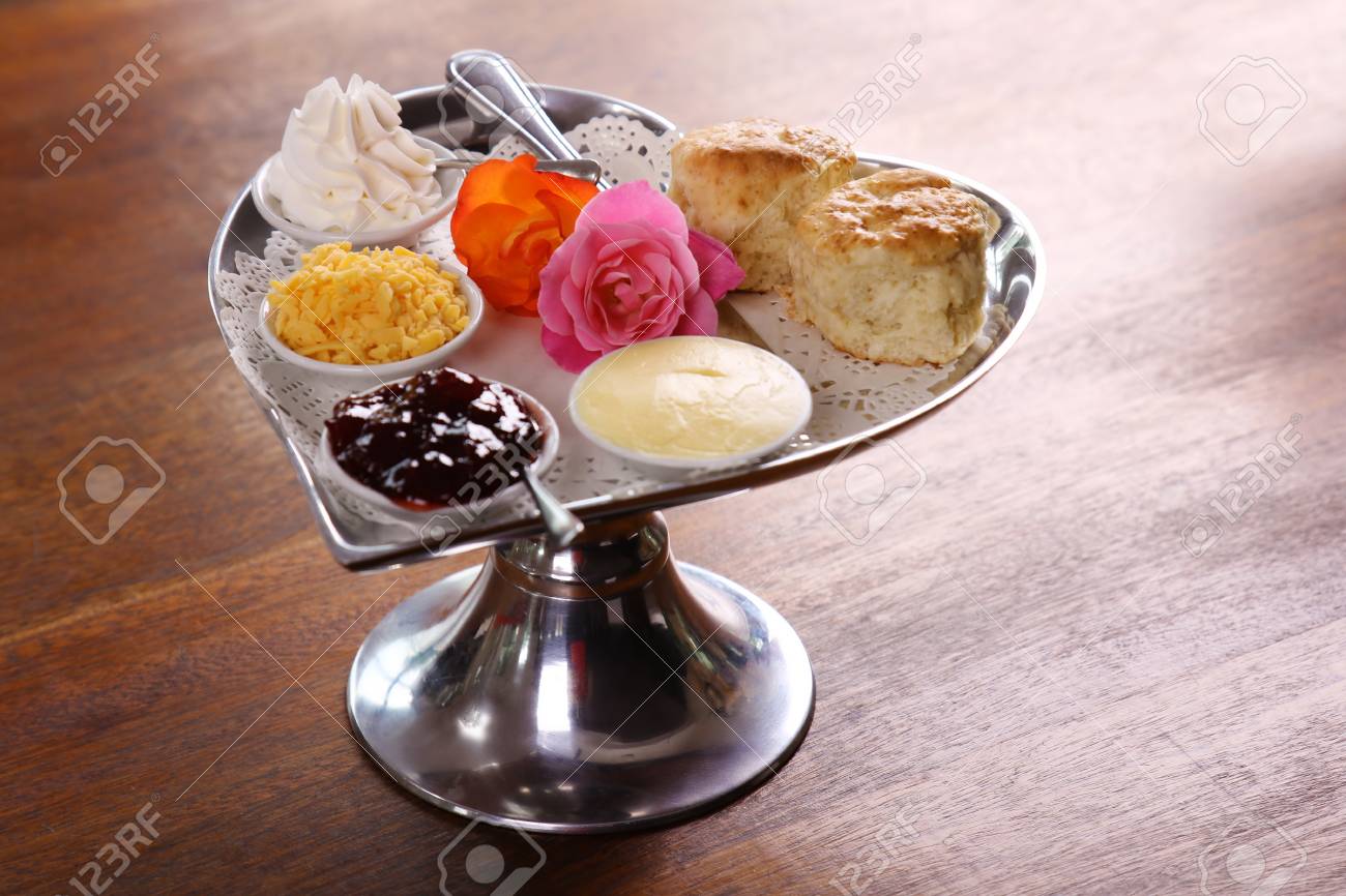 ばらチーズ クリーム添え銀ハート型トレイにおいしいバターのスコーンとジャムが木製のテーブルに保持されます の写真素材 画像素材 Image