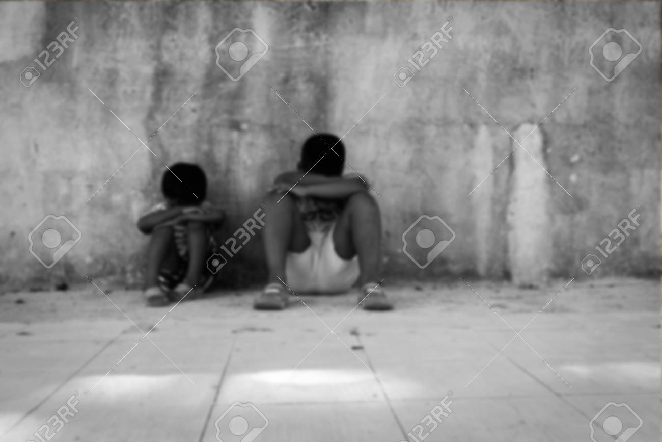 blurry of poverty asian child boy sad alone near old wall black