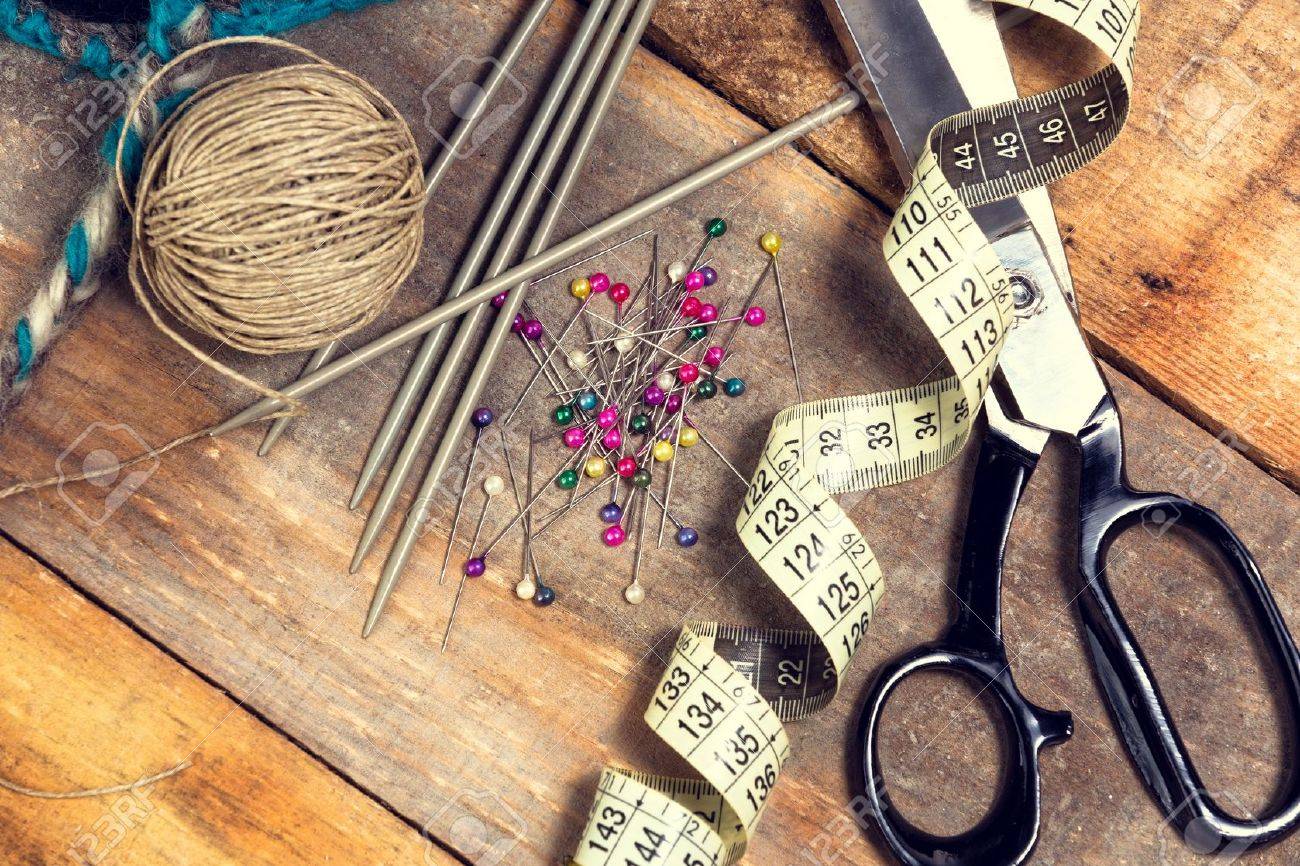 Sewing kit. Scissors, bobbins with thread, measure tape and needles on top of the old wooden table. - 36061473 Sewing kit. Scissors, bobbins with thread, measure tape and needles on top of the old wooden table. - 36061473