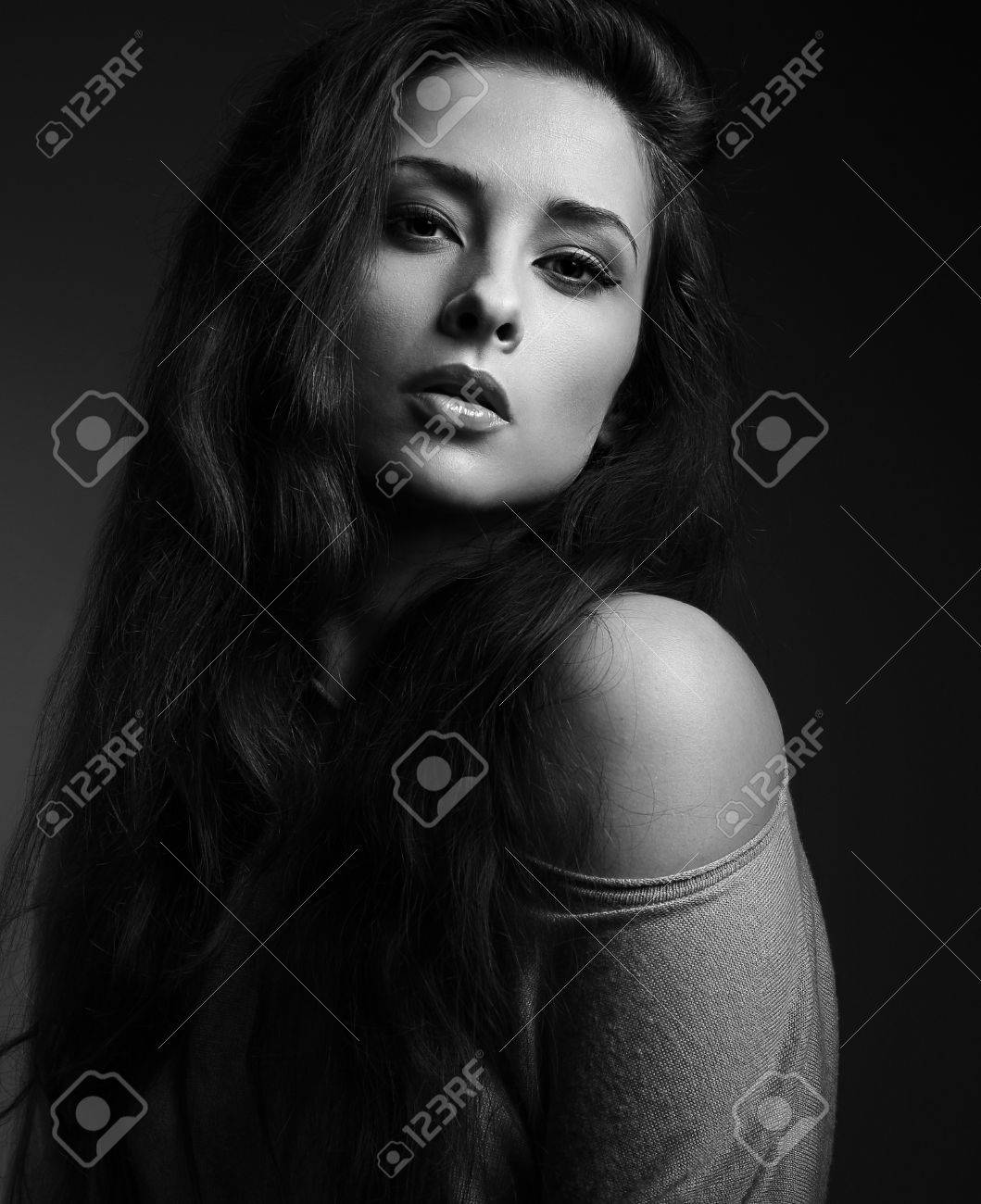 Sexy long hair woman looking hot on dark shadows background black and white closeup portrait