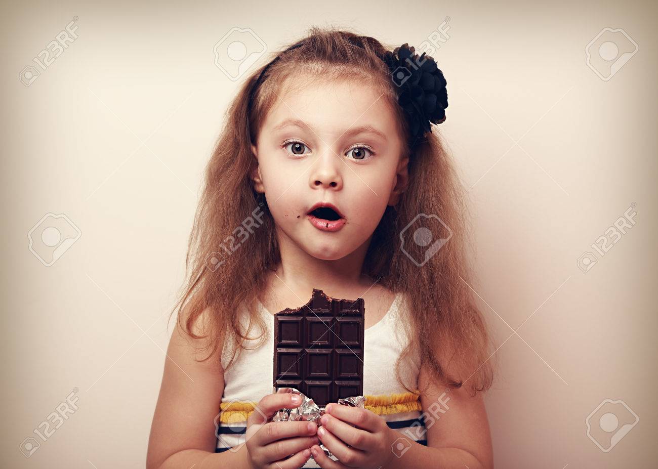 驚くべき子供女の子の大きな目で見て チョコレートを保持しています ビンテージの肖像画 の写真素材 画像素材 Image