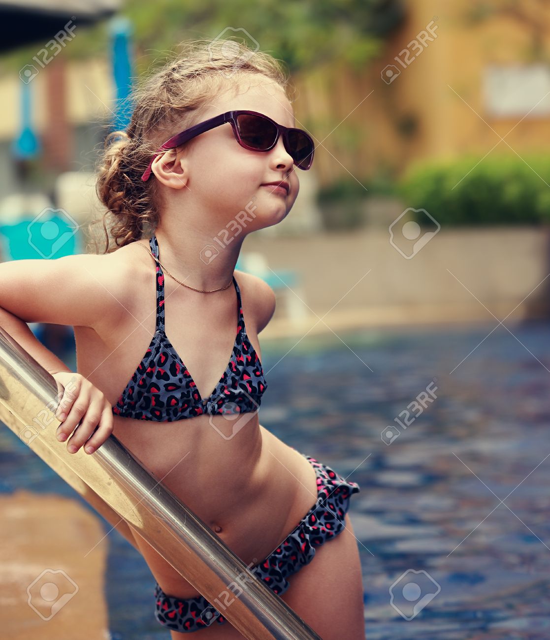 archivio fotografico poco modello femminile in posa in moda per bambini occhiali da sole e costume da bagno vicino alla piscina ritratto del primo piano