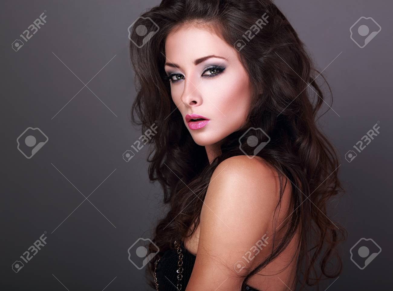 Belle Femme Avec Les Yeux Brillants Smokey De Maquillage Et Le Rouge à Lèvres Rose Volume Style De Cheveux Bouclés Sur Fond Gris