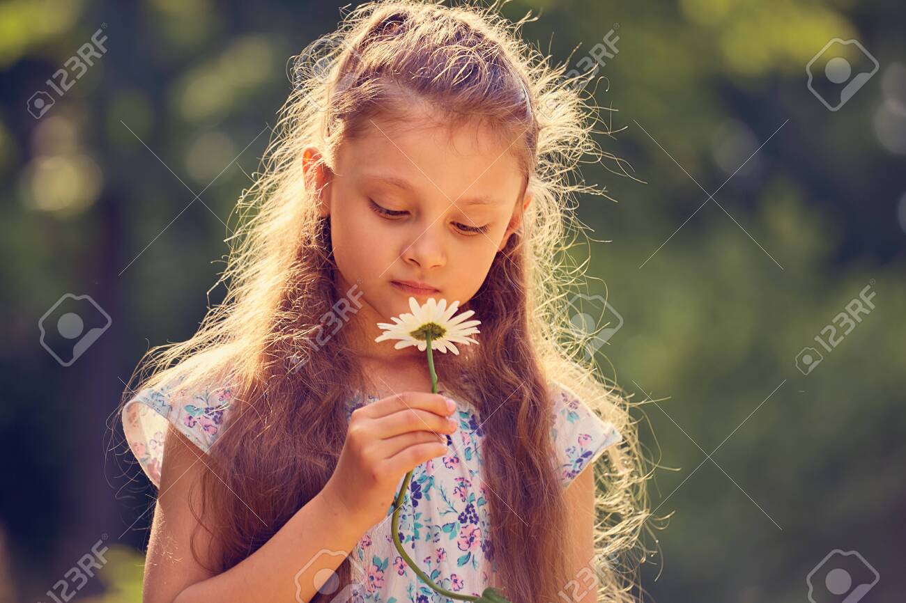 Beautiful kid girl looking on chamomile flower on nature summer green background. Closeup bright portrait - 121118637 Beautiful kid girl looking on chamomile flower on nature summer green background. Closeup bright portrait - 121118637