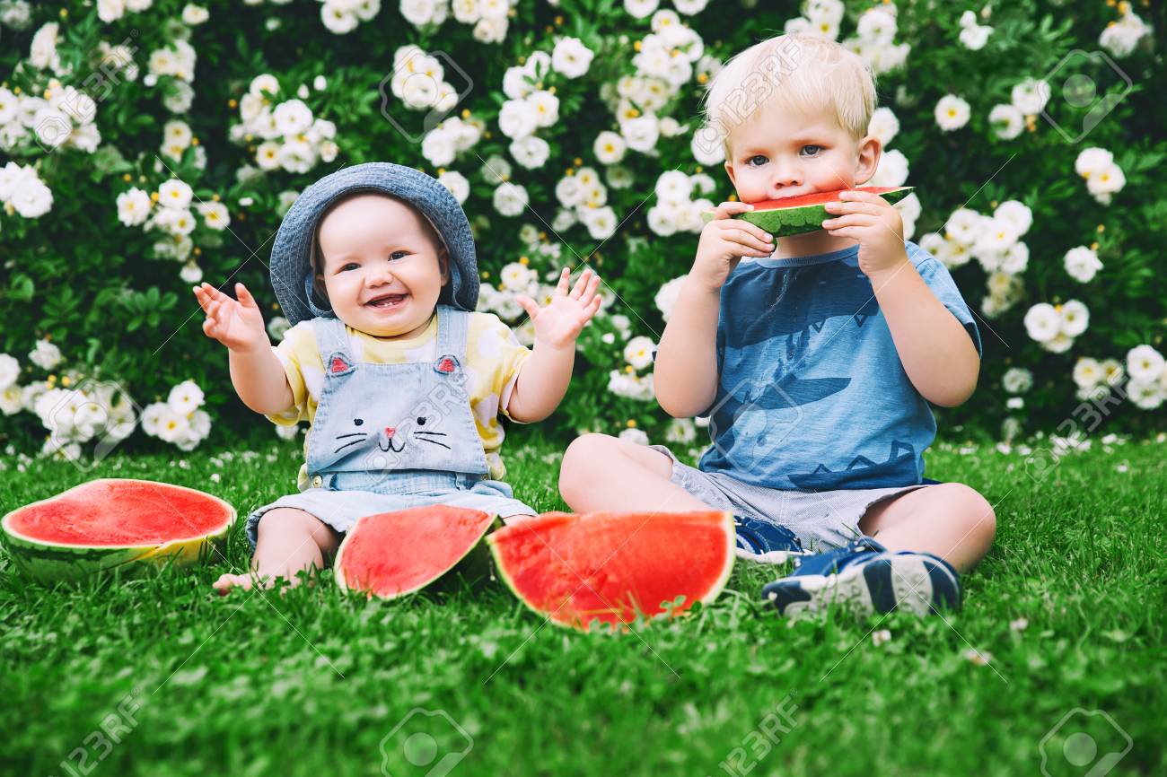 funny little kids eating watermelon on green grass on nature at