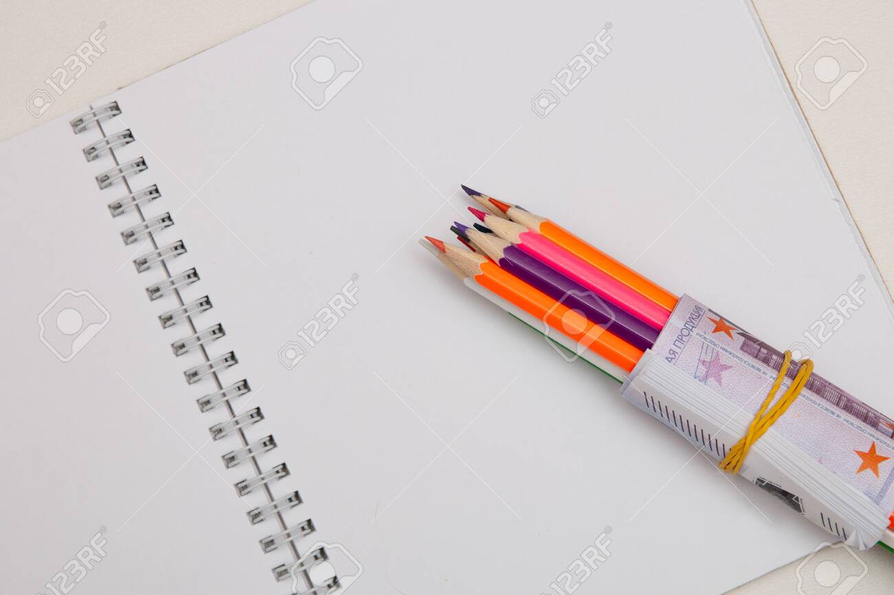 colored pencils wrapped in euro note lie on a white notebook on a white table bright copy space - 142601401 colored pencils wrapped in euro note lie on a white notebook on a white table bright copy space - 142601401