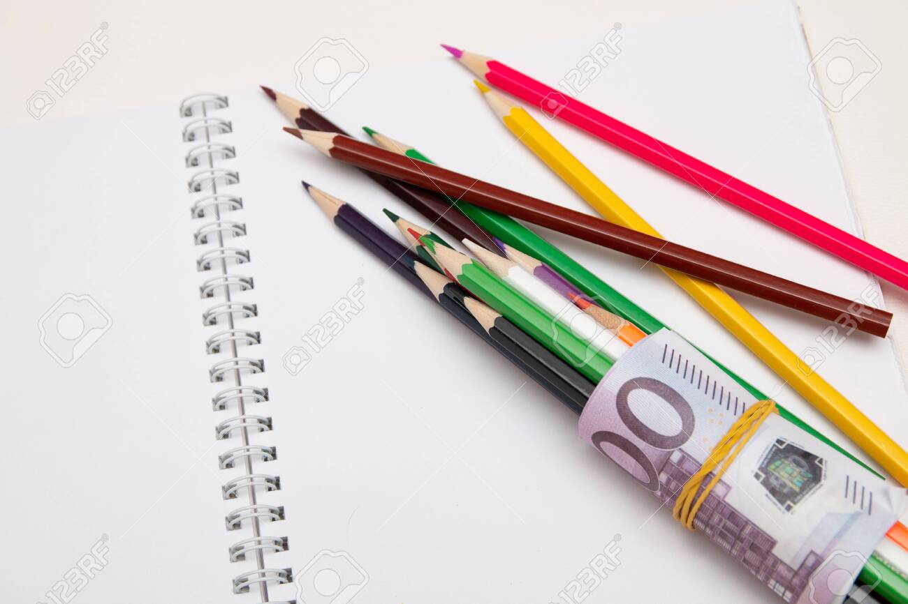 colored pencils wrapped in euro note lie on a white notebook on a white table bright copy space - 142566866 colored pencils wrapped in euro note lie on a white notebook on a white table bright copy space - 142566866