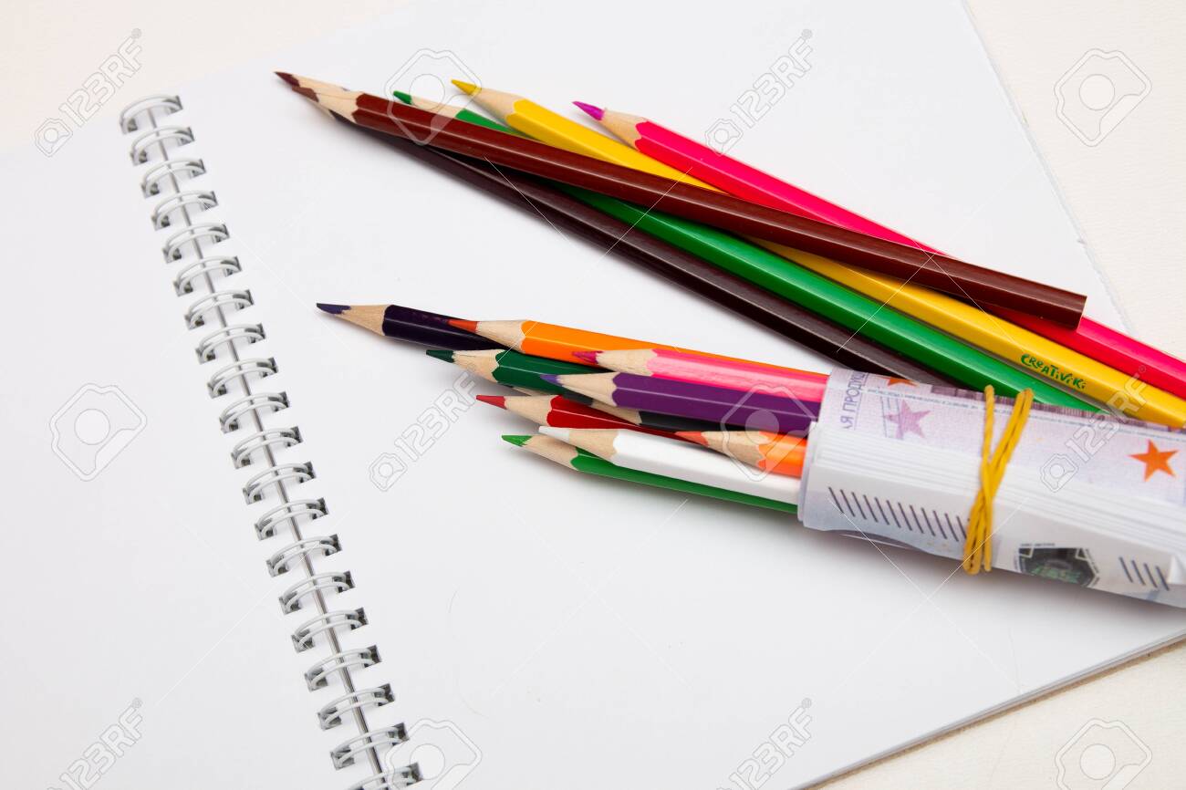 colored pencils wrapped in euro note lie on a white notebook on a white table bright copy space - 142602304 colored pencils wrapped in euro note lie on a white notebook on a white table bright copy space - 142602304