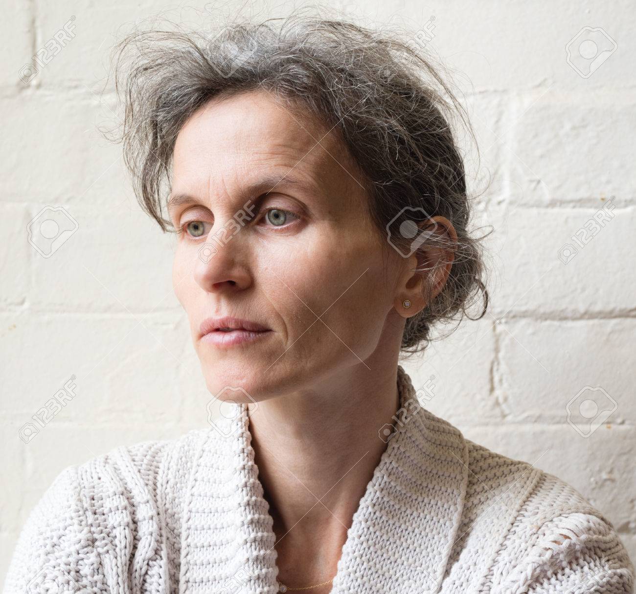 Femme Dâge Mûr Avec Les Cheveux Et Les Yeux Verts Gris Air Pensif Sur Blanc Mur De Briques De Fond - 