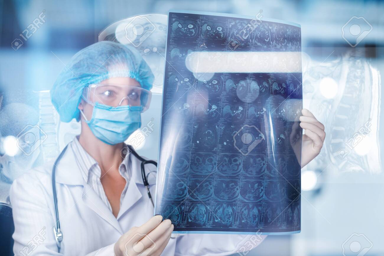 A doctor is examining a magnetic resonance imaging scan on a blurred background. - 128328557 A doctor is examining a magnetic resonance imaging scan on a blurred background. - 128328557