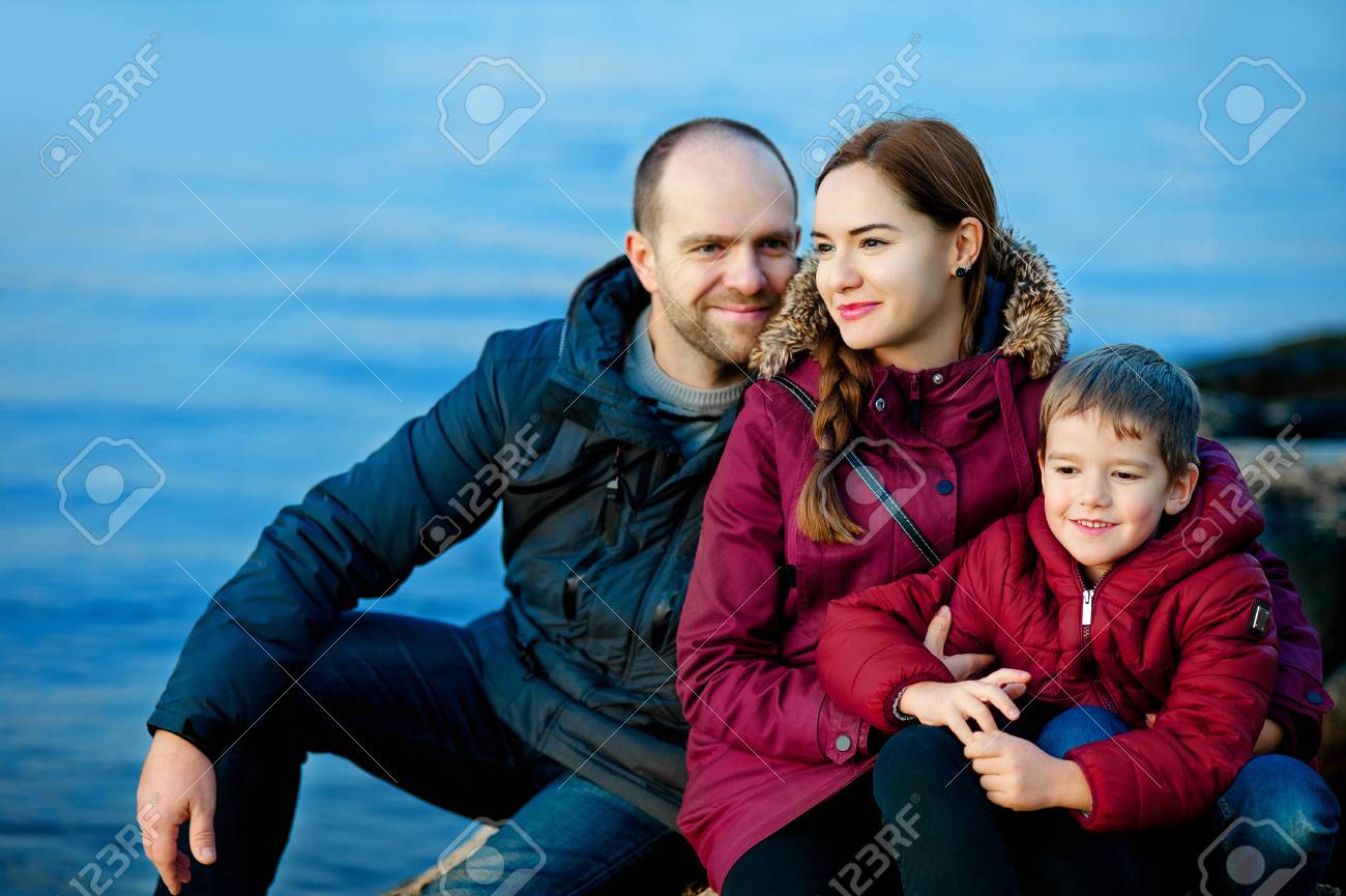 Family Mom Dad And Son Sitting On The Beach By The Sea Season