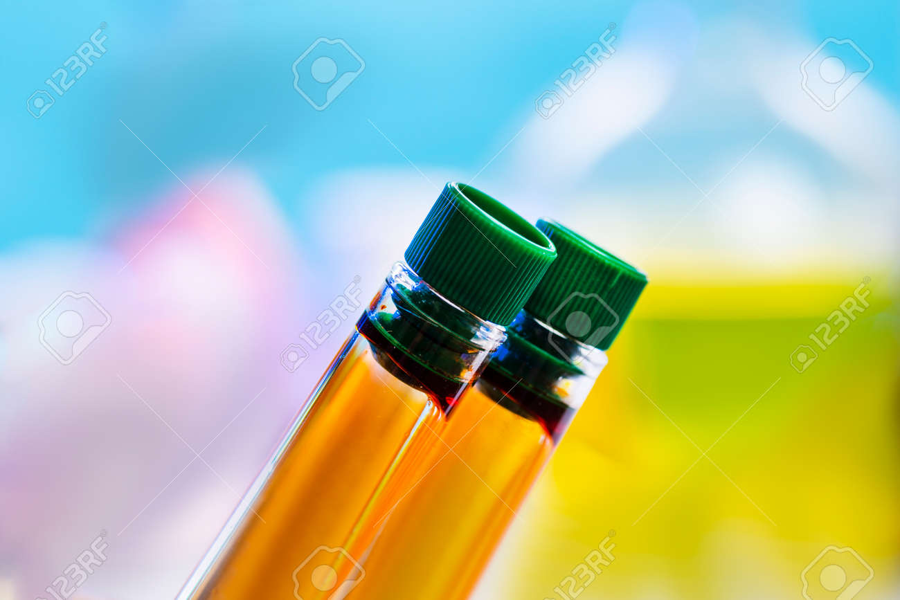 Two chemical test tubes with closed lids with orange liquid on a blue background. Urine test, delivery of urine, - 166481692 Two chemical test tubes with closed lids with orange liquid on a blue background. Urine test, delivery of urine, - 166481692