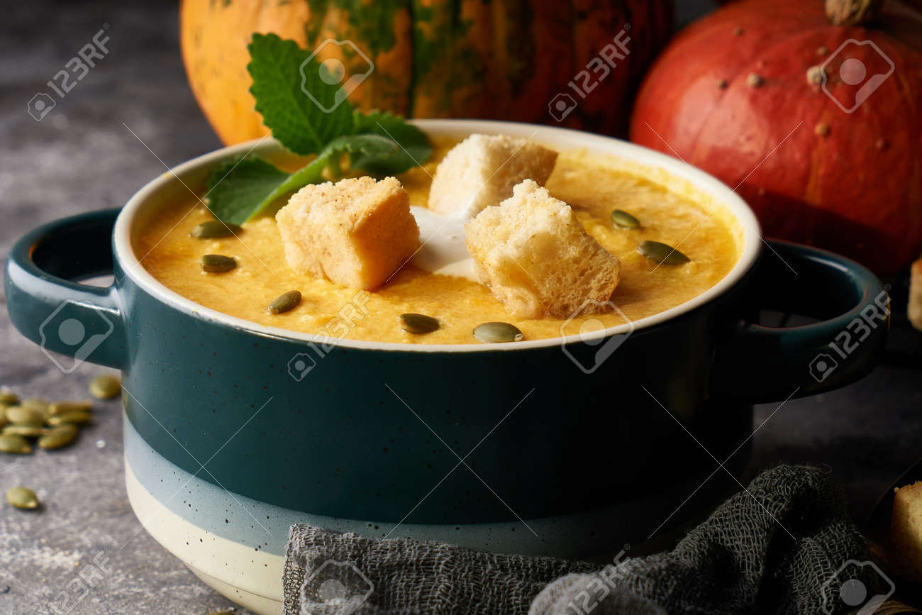 Traditional pumpkin soup puree with crackers, cream and seeds in a bowl, on a dark background Copy space - 158987045 Traditional pumpkin soup puree with crackers, cream and seeds in a bowl, on a dark background Copy space - 158987045