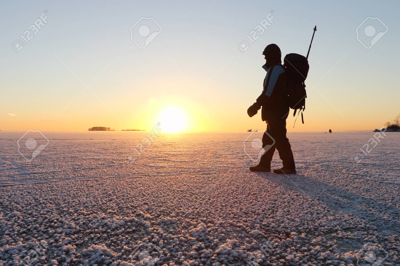 L'homme Avec Un Sac à Dos Va Sur La Glace Sur La Rivière Au Homme adulte avec une canne à pêche et un sac à dos va à la