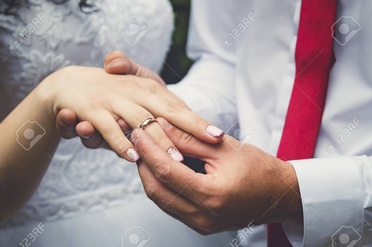 The groom puts the ring on the finger of the bride, hands close-up. - 106199430 The groom puts the ring on the finger of the bride, hands close-up. - 106199430