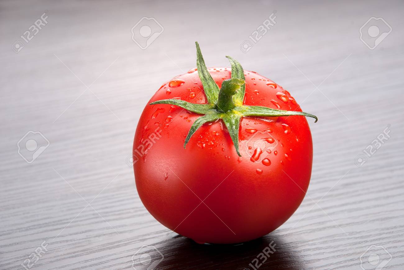 新鮮なトマトの 1 つは木製の背景に水のしずく の写真素材 画像素材 Image